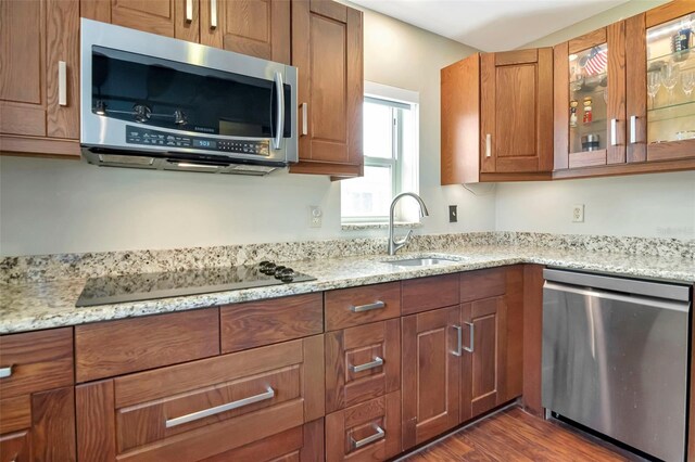 2444 Laurelwood Dr Unit A, Clearwater, FL 33763 - kitchen featuring appliances with stainless steel finishes, a sink, light stone countertops, glass insert cabinets, and brown cabinets