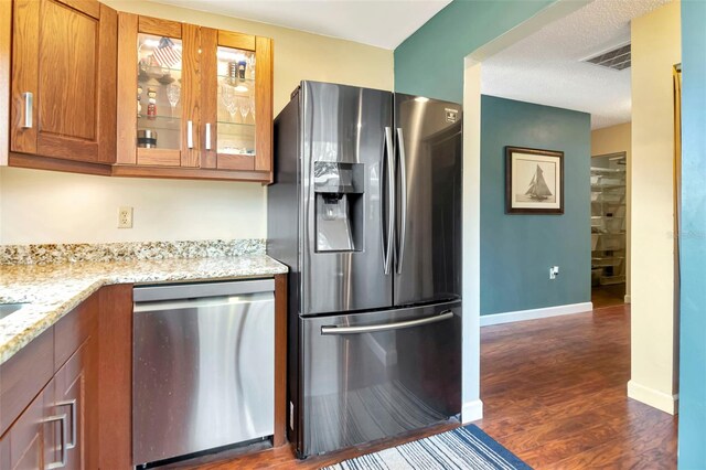 2444 Laurelwood Dr Unit A, Clearwater, FL 33763 - kitchen featuring stainless steel appliances, light stone counters, glass insert cabinets, brown cabinets, and dark wood-style flooring