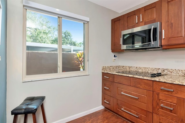2444 Laurelwood Dr Unit A, Clearwater, FL 33763 - kitchen with stainless steel microwave, black electric stovetop, baseboards, brown cabinets, and dark wood-style floors