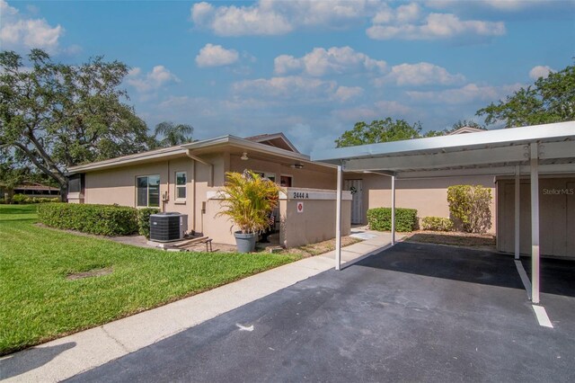 2444 Laurelwood Dr Unit A, Clearwater, FL 33763 - view of home's exterior with a yard, stucco siding, covered parking, and cooling unit