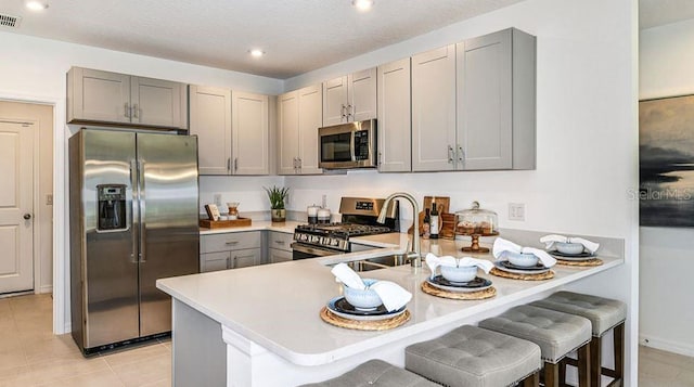 12469 Gust Ct, Hudson, FL 34669 - kitchen with stainless steel appliances, gray cabinets, a peninsula, a sink, and light countertops