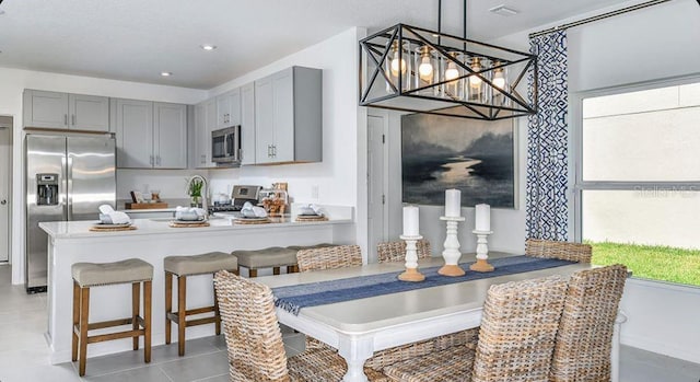 12469 Gust Ct, Hudson, FL 34669 - kitchen featuring stainless steel appliances, gray cabinetry, light tile patterned floors, a peninsula, and decorative light fixtures