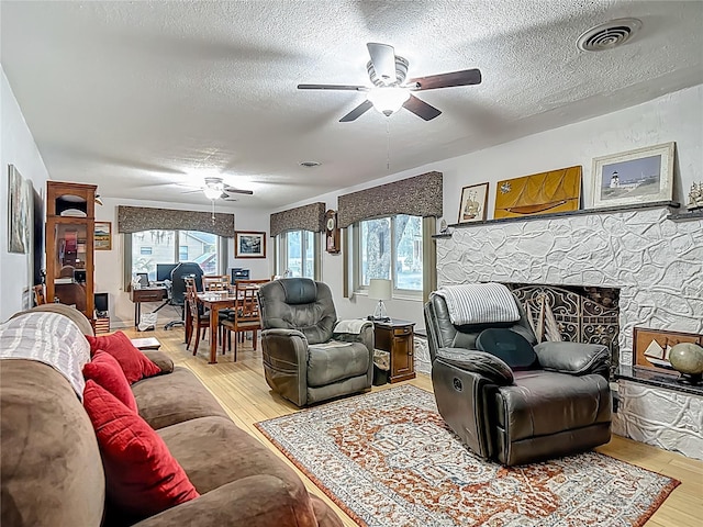 11912 Mcmullen Loop, Riverview, FL 33569 - living room featuring ceiling fan, light wood-type flooring, plenty of natural light, a textured ceiling, and a fireplace