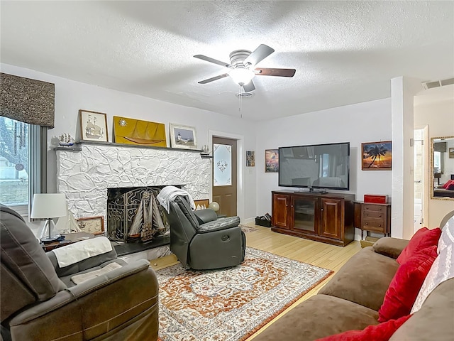 11912 Mcmullen Loop, Riverview, FL 33569 - living area with light wood-style floors, a ceiling fan, a fireplace, and a textured ceiling