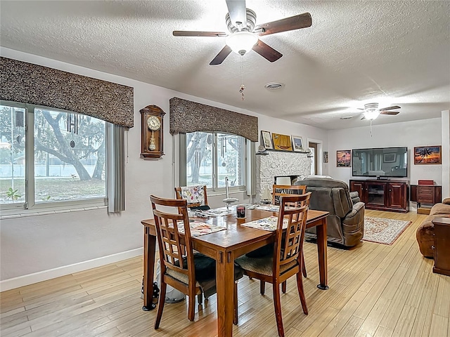 11912 Mcmullen Loop, Riverview, FL 33569 - dining space featuring a ceiling fan, a textured ceiling, a fireplace, baseboards, and light wood finished floors