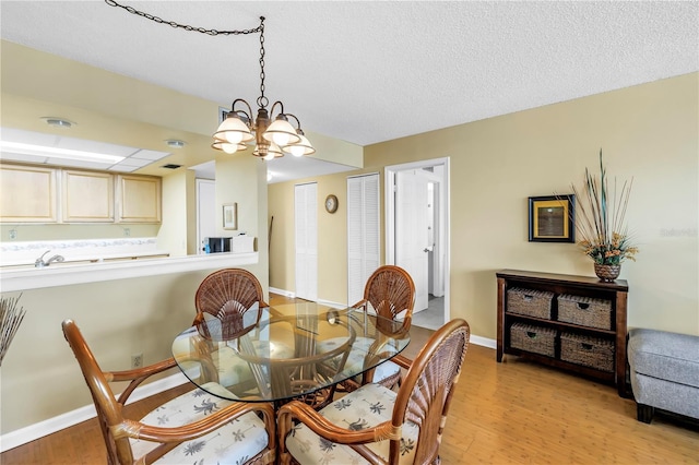 6265 Sun Blvd Unit 605, Saint Petersburg, FL 33715 - dining area with light wood finished floors, a chandelier, baseboards, and a textured ceiling