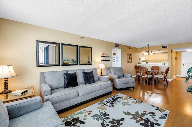 6265 Sun Blvd Unit 605, Saint Petersburg, FL 33715 - living room with a chandelier, a textured ceiling, hardwood / wood-style floors, and baseboards