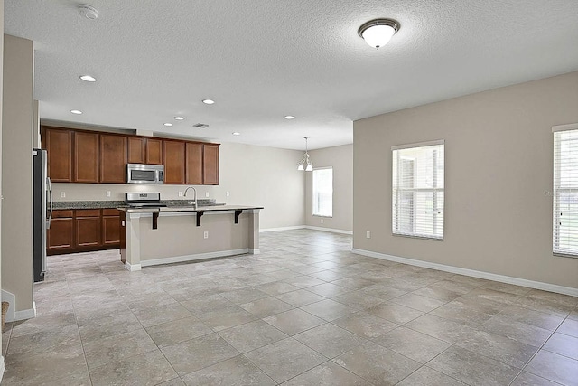 16016 Persimmon Grove Dr, Lithia, FL 33547 - kitchen featuring stainless steel appliances, a breakfast bar, recessed lighting, a sink, and a textured ceiling