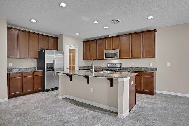 16016 Persimmon Grove Dr, Lithia, FL 33547 - kitchen featuring appliances with stainless steel finishes, baseboards, a center island with sink, a kitchen breakfast bar, and recessed lighting