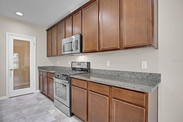 16016 Persimmon Grove Dr, Lithia, FL 33547 - kitchen with appliances with stainless steel finishes, dark stone countertops, baseboards, and recessed lighting