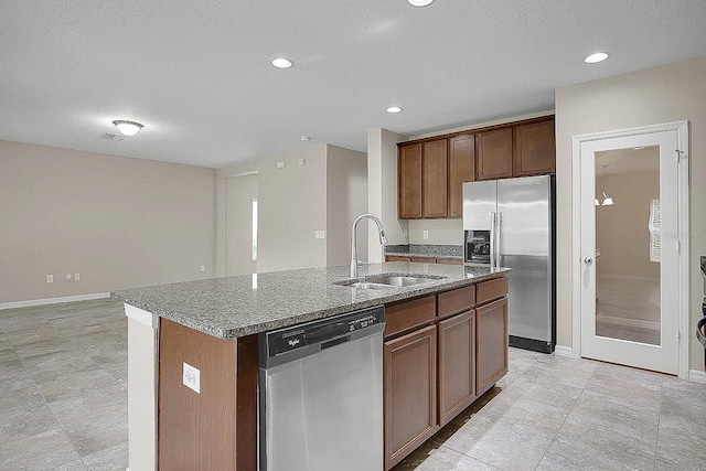 16016 Persimmon Grove Dr, Lithia, FL 33547 - kitchen with appliances with stainless steel finishes, a sink, light stone countertops, an island with sink, and a textured ceiling
