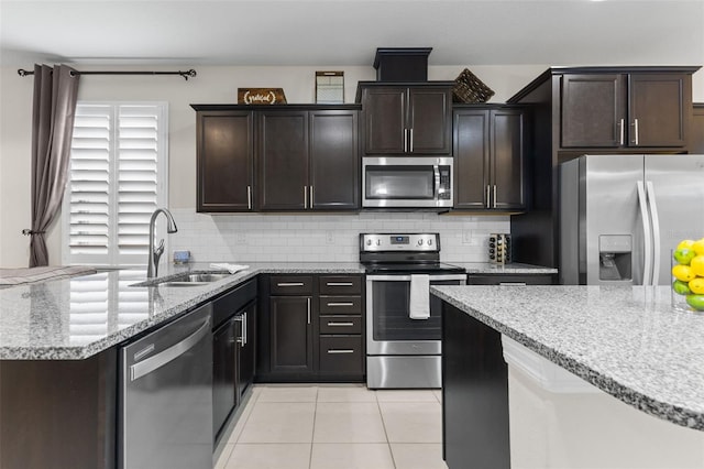 1321 Custer Bayou St, Ruskin, FL 33570 - kitchen featuring stainless steel appliances, light tile patterned floors, tasteful backsplash, light stone countertops, and a sink