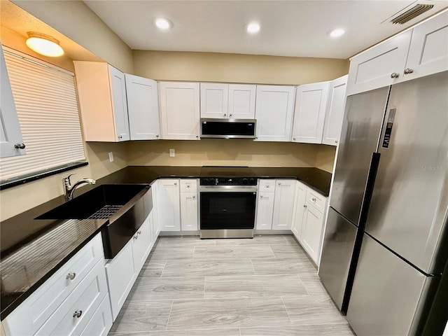 440 89th Ave, St Pete Beach, FL 33706 - kitchen with appliances with stainless steel finishes, dark countertops, white cabinetry, recessed lighting, and a sink