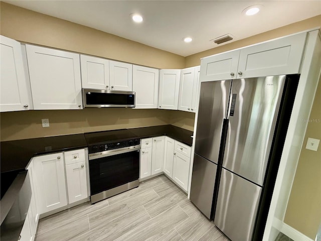440 89th Ave, St Pete Beach, FL 33706 - kitchen featuring appliances with stainless steel finishes, white cabinets, dark countertops, and recessed lighting