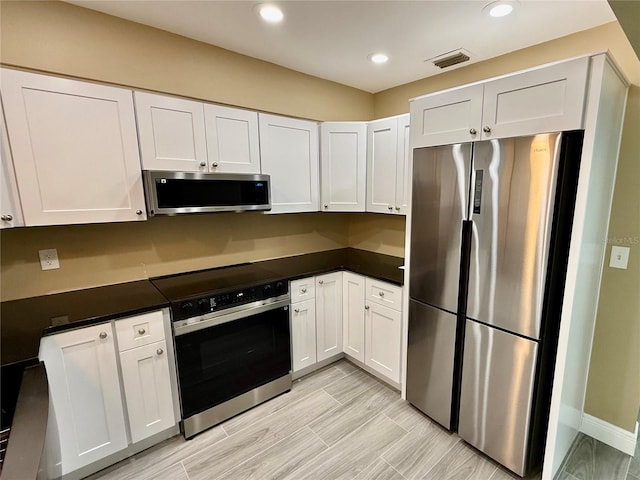 440 89th Ave, St Pete Beach, FL 33706 - kitchen featuring appliances with stainless steel finishes, dark countertops, white cabinets, recessed lighting, and baseboards
