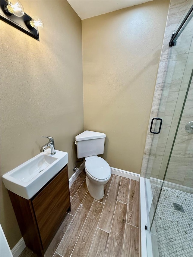 440 89th Ave, St Pete Beach, FL 33706 - bathroom with vanity, toilet, a shower stall, wood finish floors, and baseboards