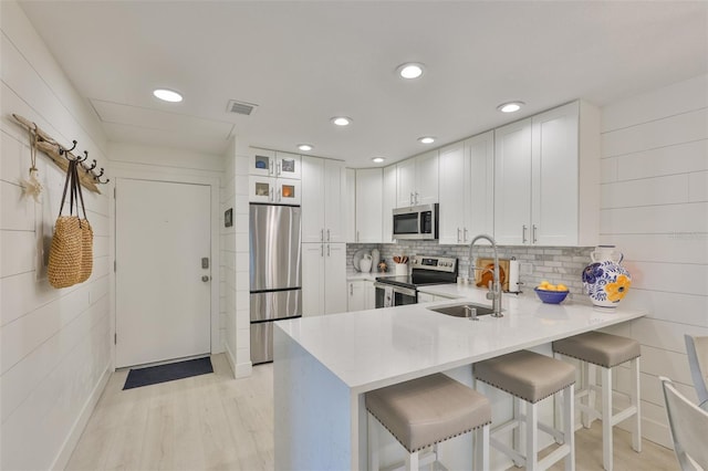 230 Medallion Blvd Unit F, Madeira Beach, FL 33708 - kitchen featuring appliances with stainless steel finishes, a sink, a peninsula, light countertops, and a breakfast bar