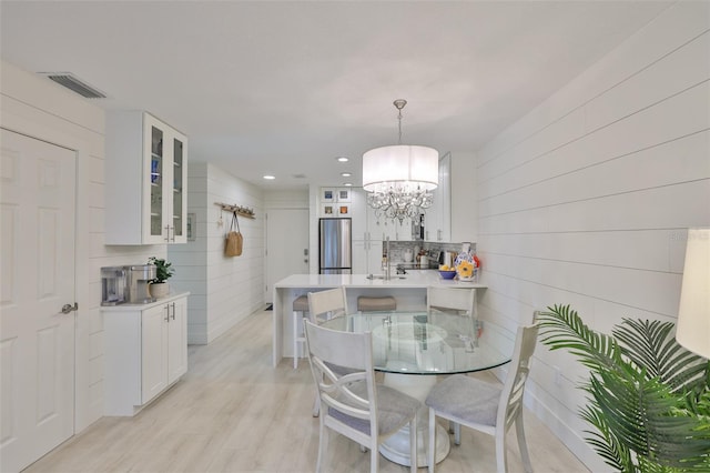 230 Medallion Blvd Unit F, Madeira Beach, FL 33708 - dining area featuring a chandelier, light wood-style floors, recessed lighting, and wooden walls