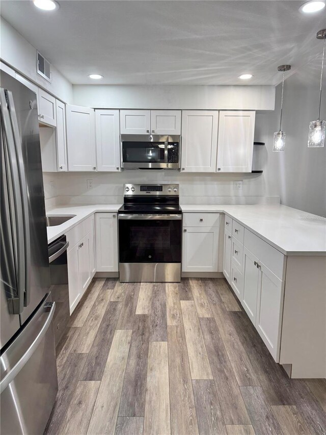2690 Coral Landings Blvd Unit 217, Palm Harbor, FL 34684 - kitchen with stainless steel appliances, a peninsula, wood finished floors, light countertops, and recessed lighting