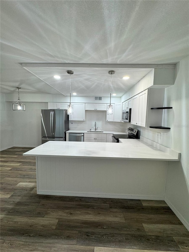 2690 Coral Landings Blvd Unit 217, Palm Harbor, FL 34684 - kitchen with stainless steel appliances, a sink, a peninsula, white cabinets, and dark wood-style floors