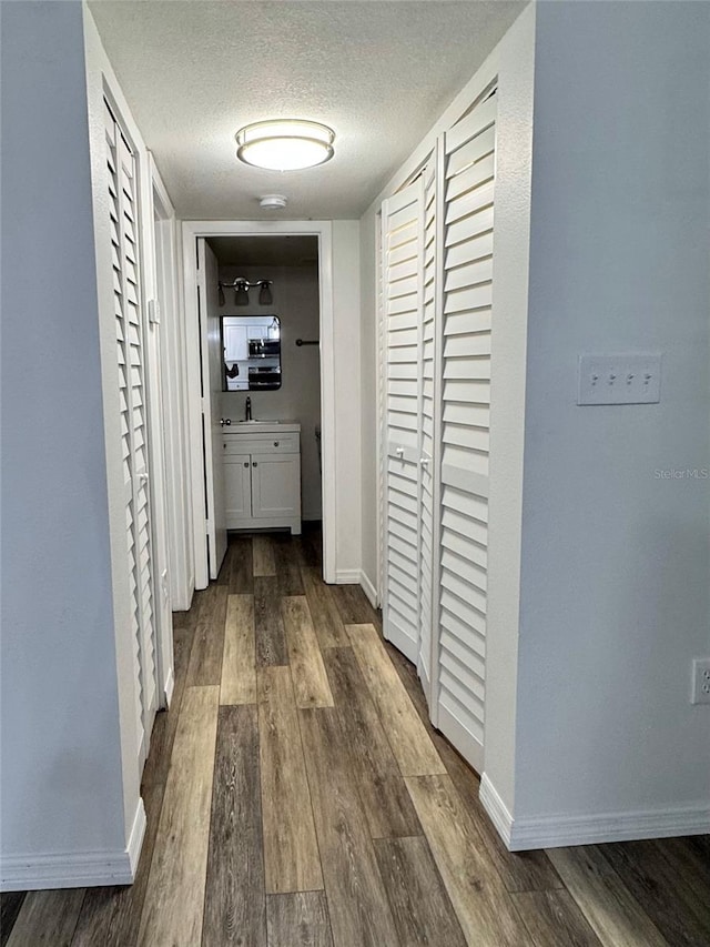 2690 Coral Landings Blvd Unit 217, Palm Harbor, FL 34684 - hall featuring a textured ceiling, baseboards, dark wood-style flooring, and a sink