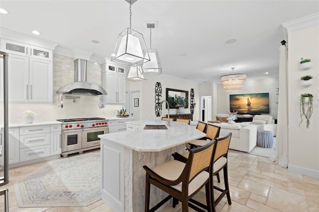 703 Monte Cristo Blvd, Tierra Verde, FL 33715 - kitchen featuring range with two ovens, ventilation hood, a sink, tasteful backsplash, and a breakfast bar