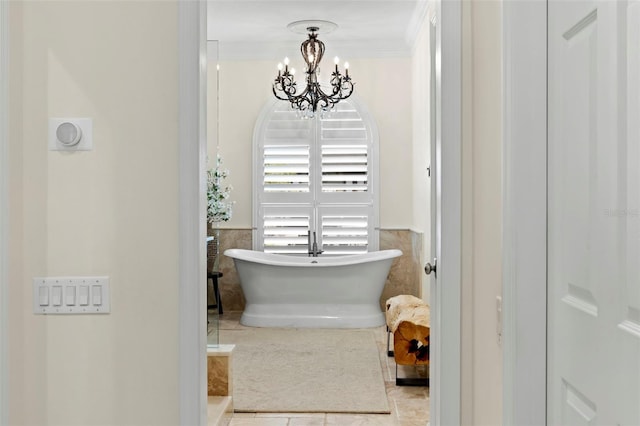 703 Monte Cristo Blvd, Tierra Verde, FL 33715 - bathroom with a chandelier, a freestanding bath, tile patterned flooring, tile walls, and ornamental molding