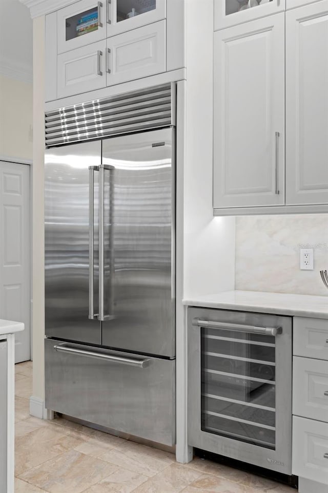703 Monte Cristo Blvd, Tierra Verde, FL 33715 - kitchen featuring stainless steel built in fridge, wine cooler, crown molding, light countertops, and white cabinets