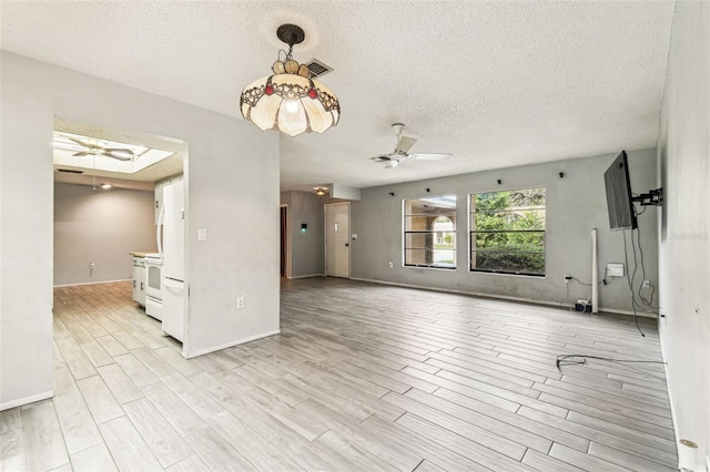 2410 Covington Ave, Spring Hill, FL 34608 - unfurnished living room featuring a ceiling fan, light wood-style flooring, a textured ceiling, baseboards, and a skylight
