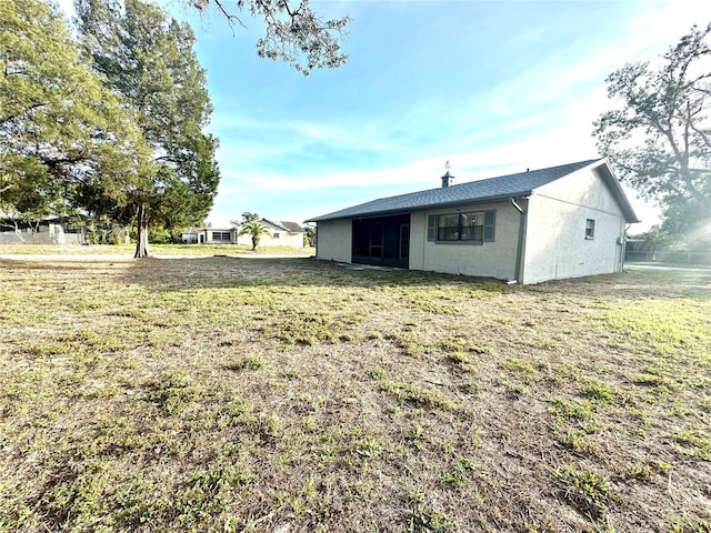 13100 Serpentine Dr, Hudson, FL 34667 - rear view of house with a lawn, stucco siding, and a chimney