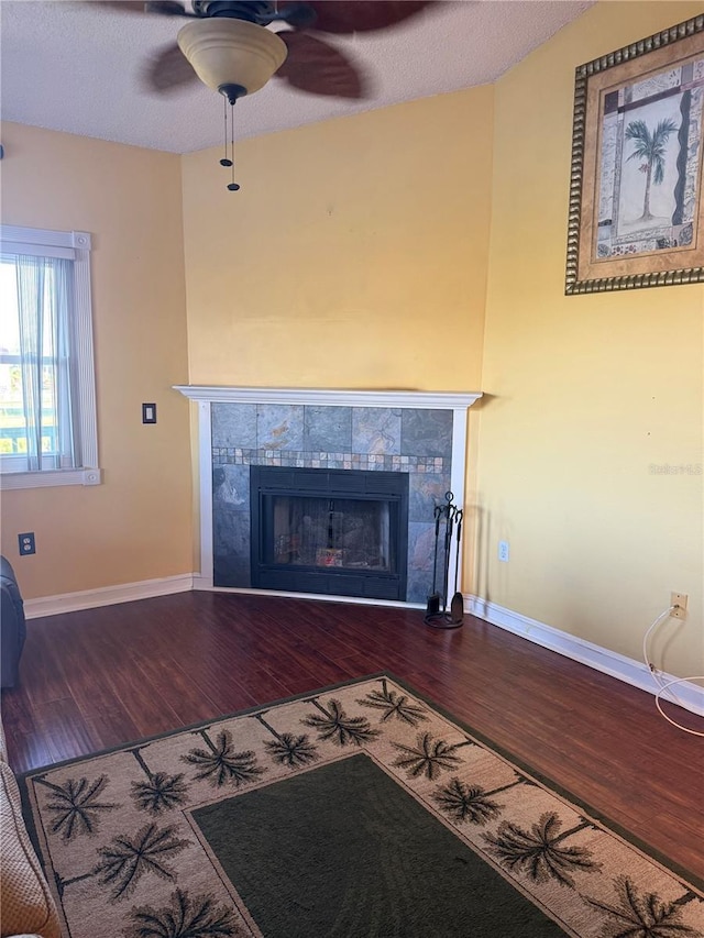 3338 Fernleaf Dr, Hernando Beach, FL 34607 - detailed view of wood finished floors, a tile fireplace, a ceiling fan, baseboards, and a textured ceiling