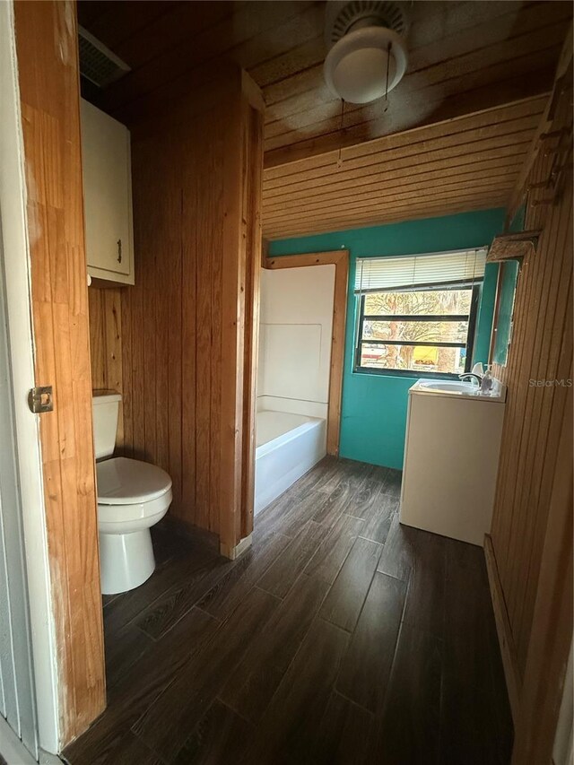 3338 Fernleaf Dr, Hernando Beach, FL 34607 - bathroom with wood finished floors, toilet, a tub to relax in, vanity, and wood walls