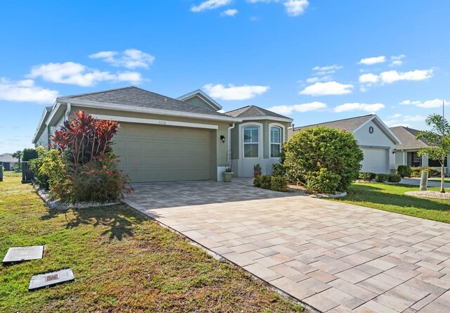1110 Jasmine Creek Ct, Sun City Center, FL 33573 - ranch-style house with a garage, decorative driveway, a front lawn, and stucco siding