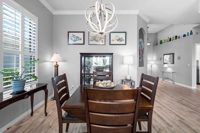 1110 Jasmine Creek Ct, Sun City Center, FL 33573 - dining room featuring light wood finished floors, a chandelier, baseboards, arched walkways, and ornamental molding