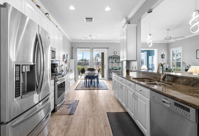 1110 Jasmine Creek Ct, Sun City Center, FL 33573 - kitchen with appliances with stainless steel finishes, a sink, ornamental molding, white cabinets, and light wood-style floors