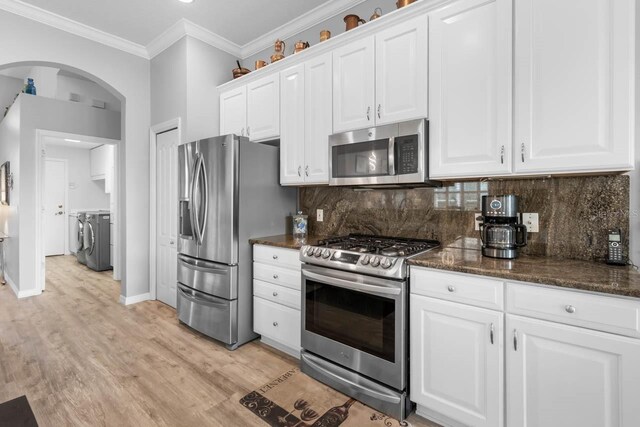 1110 Jasmine Creek Ct, Sun City Center, FL 33573 - kitchen featuring appliances with stainless steel finishes, washer and dryer, arched walkways, baseboards, and white cabinetry