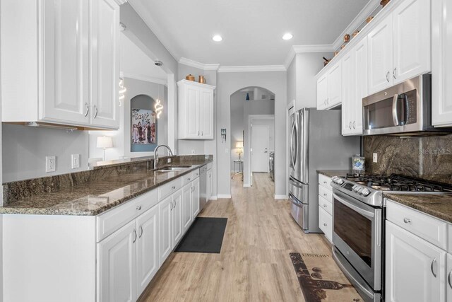 1110 Jasmine Creek Ct, Sun City Center, FL 33573 - kitchen with stainless steel appliances, a sink, arched walkways, white cabinets, and crown molding