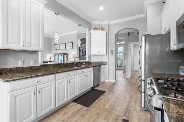 1110 Jasmine Creek Ct, Sun City Center, FL 33573 - kitchen with a sink, arched walkways, stainless steel appliances, white cabinets, and crown molding