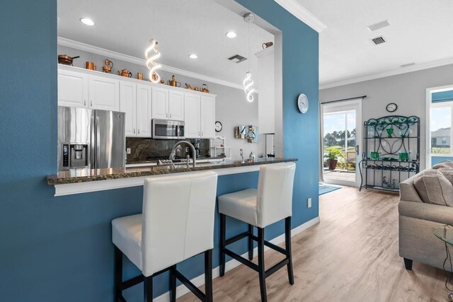 1110 Jasmine Creek Ct, Sun City Center, FL 33573 - kitchen with stainless steel appliances, backsplash, ornamental molding, a kitchen bar, and dark stone countertops