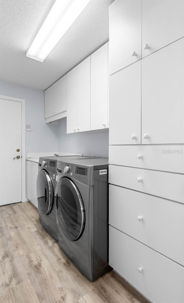 1110 Jasmine Creek Ct, Sun City Center, FL 33573 - laundry room with cabinet space, washer and clothes dryer, light wood-style floors, and a textured ceiling
