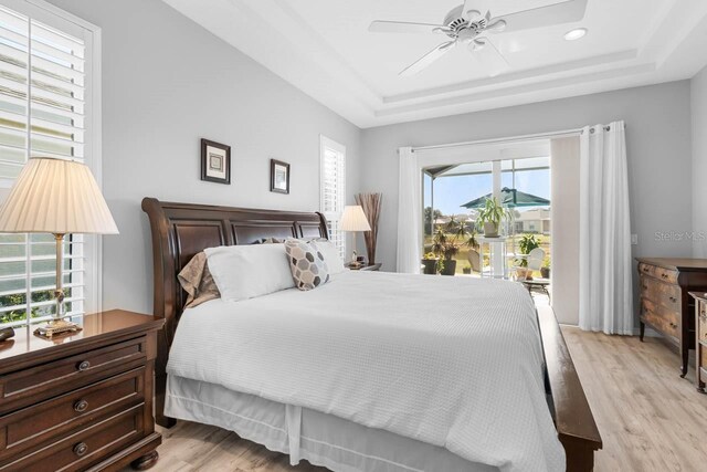 1110 Jasmine Creek Ct, Sun City Center, FL 33573 - bedroom with a raised ceiling, light wood finished floors, ceiling fan, recessed lighting, and access to outside