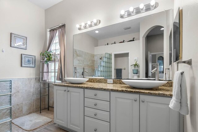 1110 Jasmine Creek Ct, Sun City Center, FL 33573 - full bathroom featuring double vanity, tile walls, tiled shower, and wainscoting