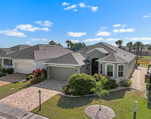 1110 Jasmine Creek Ct, Sun City Center, FL 33573 - ranch-style house with decorative driveway, an attached garage, roof with shingles, and stucco siding