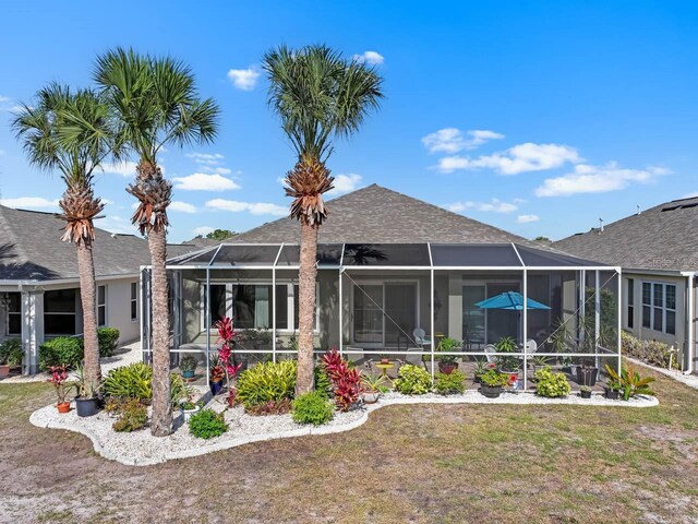 1110 Jasmine Creek Ct, Sun City Center, FL 33573 - rear view of house with a lawn, roof with shingles, and glass enclosure