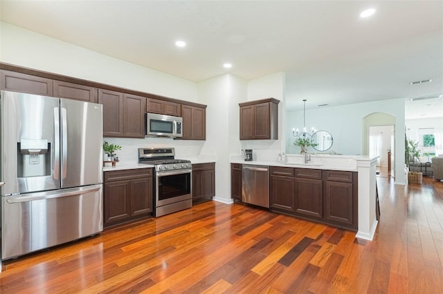 20403 Sultana Ct, Tampa, FL 33647 - kitchen with appliances with stainless steel finishes, a peninsula, dark wood-style floors, light countertops, and dark brown cabinetry