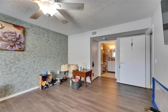 9481 Highland Oak Dr Unit 1511, Tampa, FL 33647 - bedroom with wood finished floors, a textured ceiling, wallpapered walls, a ceiling fan, and ensuite bath