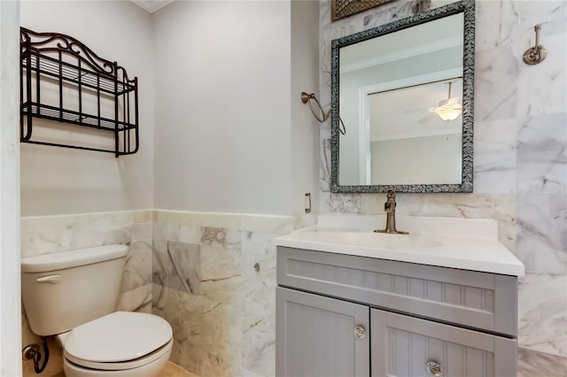 1242 Bermuda St, Clearwater, FL 33755 - half bath with tile walls, vanity, toilet, a ceiling fan, and wainscoting
