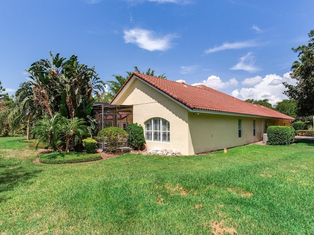 10504 Echo Lake Dr, Odessa, FL 33556 - view of side of property featuring a tiled roof, a lawn, stucco siding, and glass enclosure