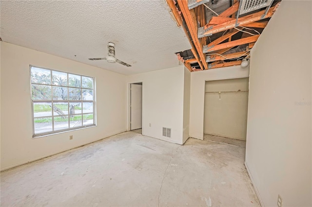 7033 Wentworth Way, New Port Richey, FL 34655 - unfurnished bedroom featuring unfinished concrete floors, a textured ceiling, and a closet