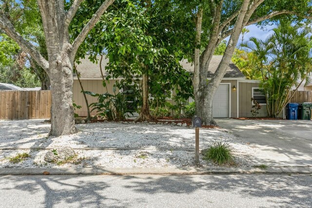 4021 Vana Dr, Sarasota, FL 34241 - view of property hidden behind natural elements with driveway, a garage, and roof with shingles